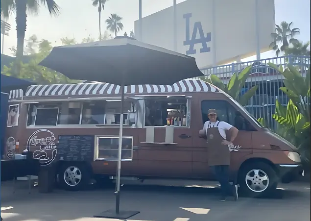 Paulo is smiling and standing in front of Granno Cafe Truck at Dodger's Stadium.