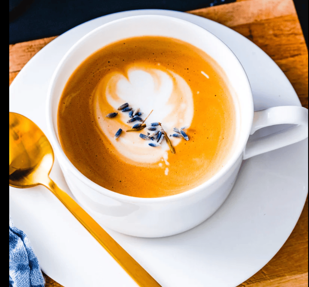 lavendar latte on a white plate with a gold spoon