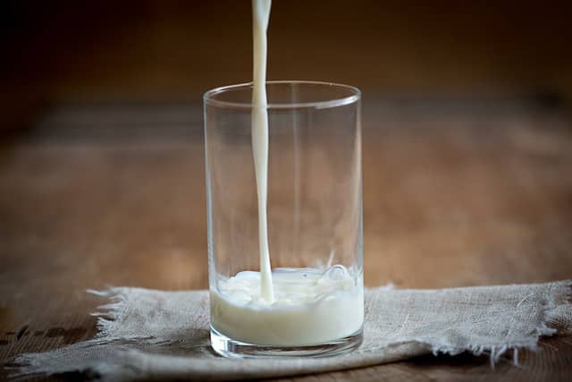 cup with cold milk being poured in