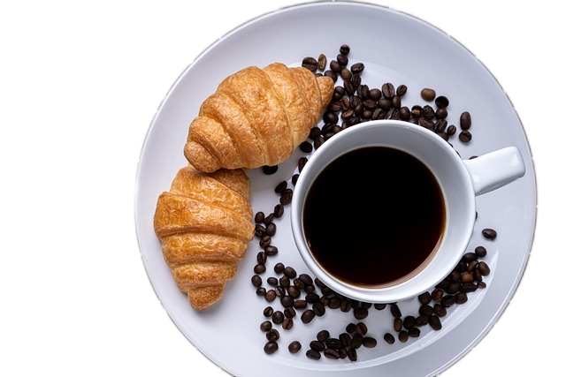 a white plate with 2 croissants, coffee cup, and coffee beans