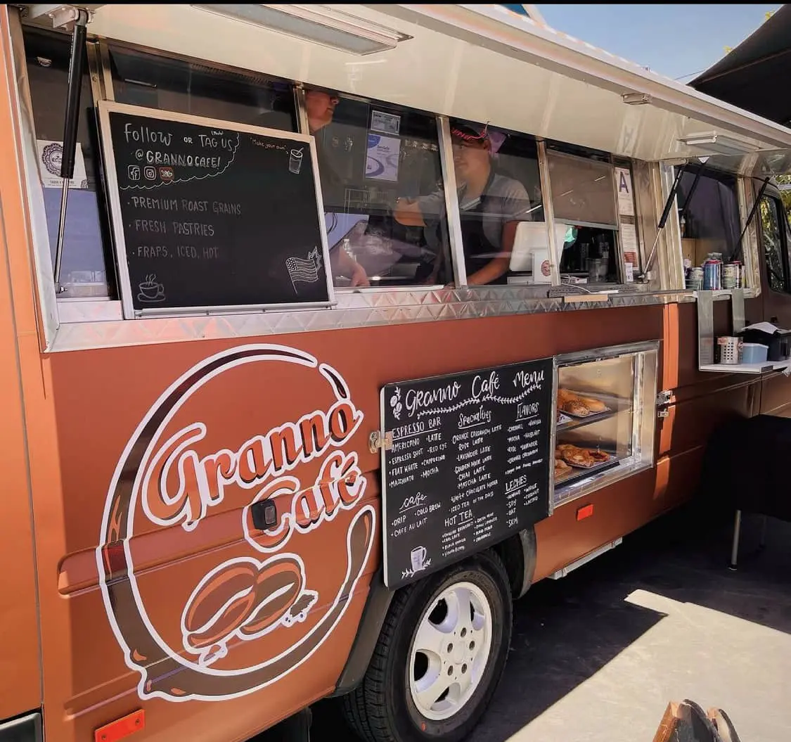 An angled shot Granno Cafe mobile truck. Windows, menu, and a display with an array of fresh pastries.